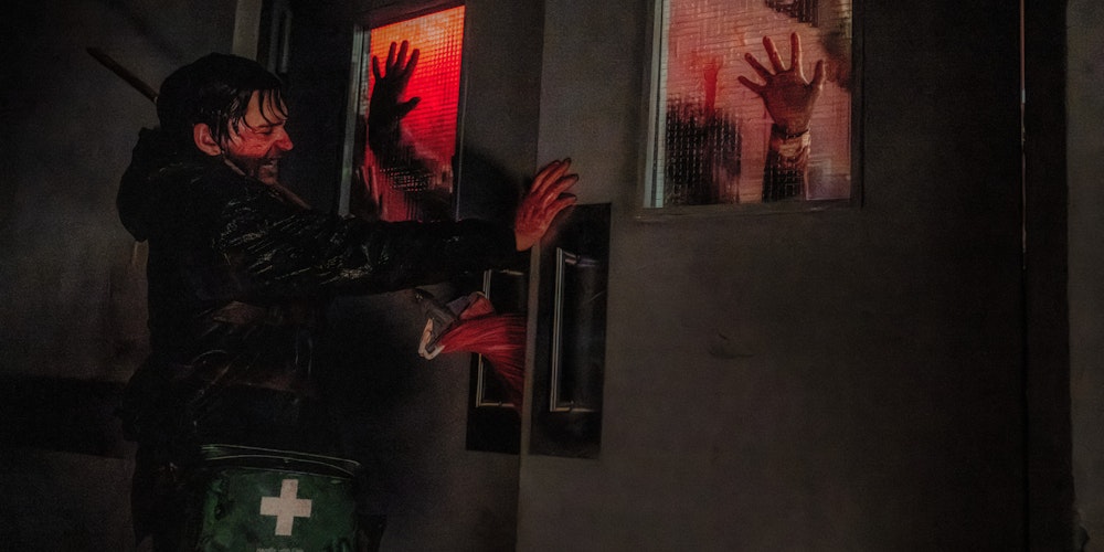 Resident Evil still: a courier holding industrial doors against a red-lit crowd, Jam Jar